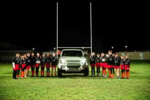 Photographie des joueurs avec le maillot Defender du club de l'école de rugby des Albères de Saint-André. Événement sportif pour la marque Defender de Land Rover Perpignan pour la Coupe du monde de rugby 2023. Le véhicule est sur le terrain de rugby.