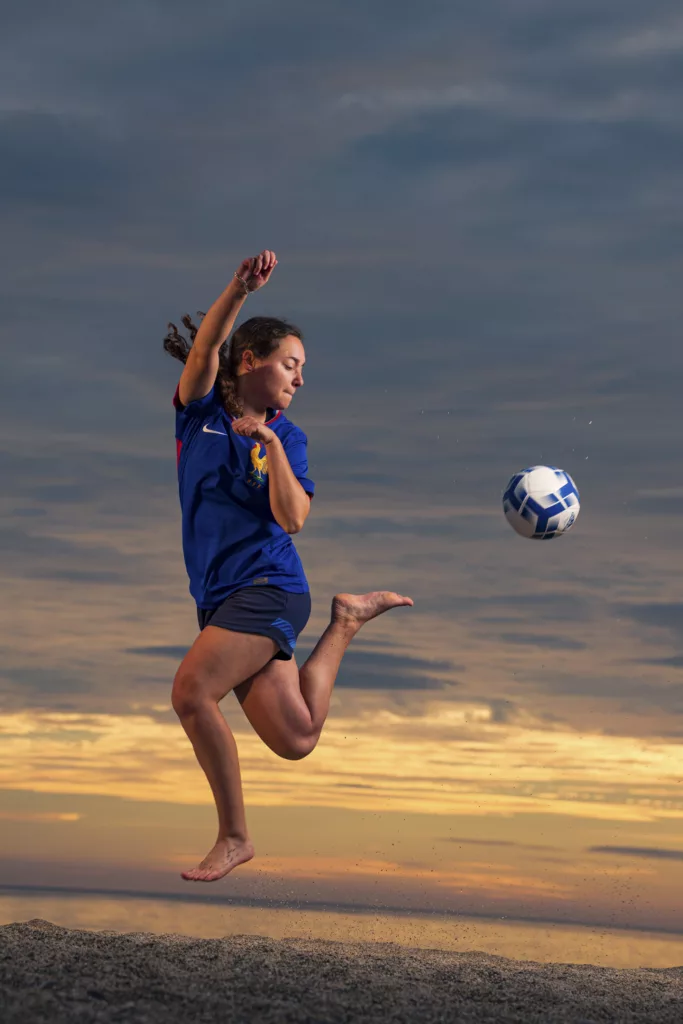 sport féminin, athlète de football féminine à la plage en train d'effectuer un dribble aérien.